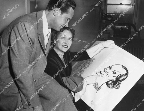 William Holden & Gloria Swanson look over caricature - 11022-021