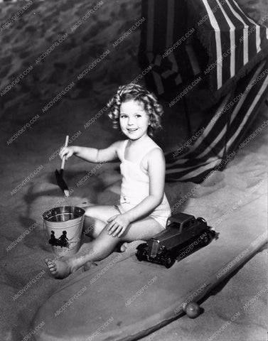 candid Shirley Temple plating in the sand with toy cars 934-20