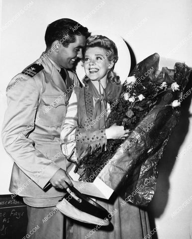candid Tyrone Power surprises Alice Faye w a bunch of flowers 2123-08