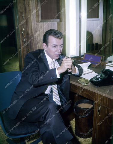 Bobby Darin firing up his pipe sitting at the desk 8b20-13784