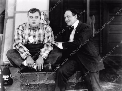Harry Houdini pulls cards out of Roscoe Fatty Arbuckle's ear 8b20-1440