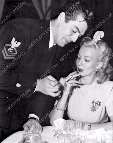 candid Victor Mature gives Carole Landis a light 8b20-15622