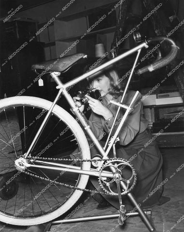crp-14363 1940 candid Evelyn Keyes w her camera and new (vintage) exercise bicycle crp-14363
